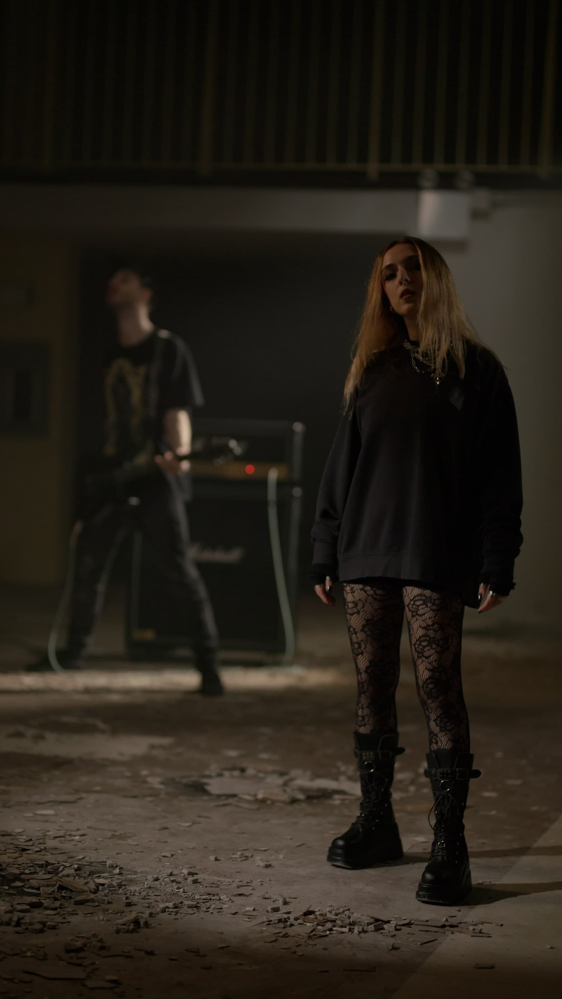 BRENNA in an industrial space with guitarist and Marshall amp behind her